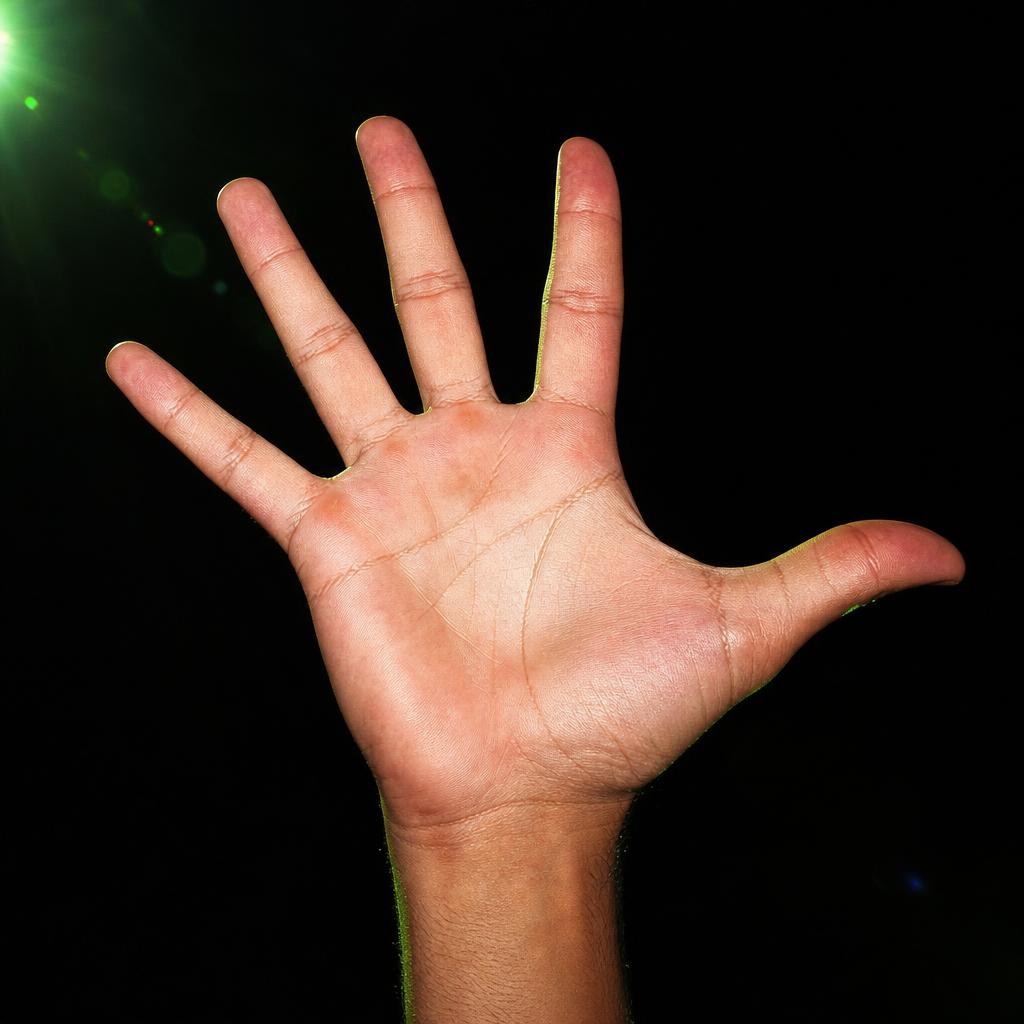 A hand raised against pitch black, fingers fanned like turkey feathers, thumb out as the head, lit by green lens flare